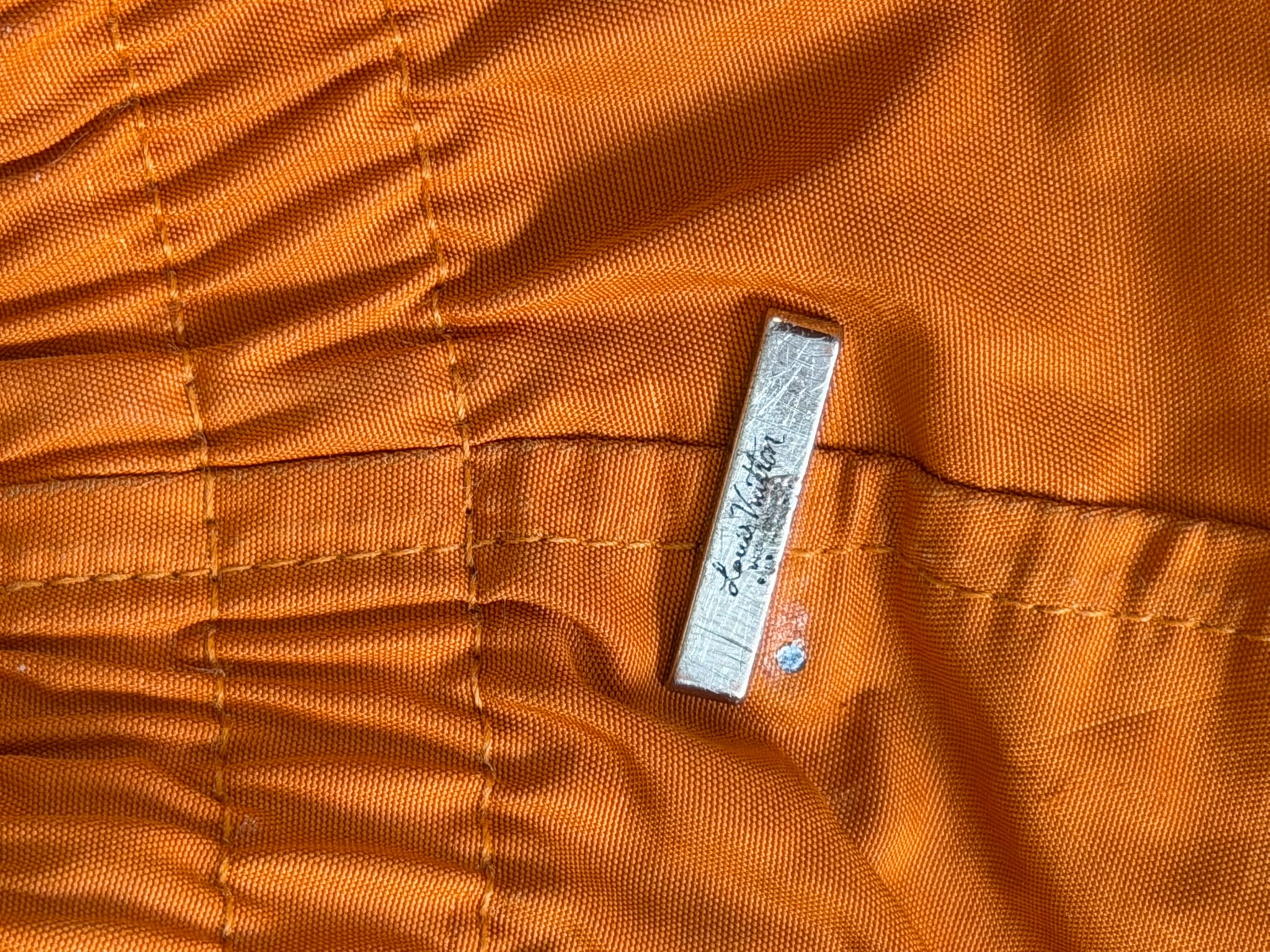 Close-up of tonal Louis Vuitton Monogram fabric on orange swim shorts
