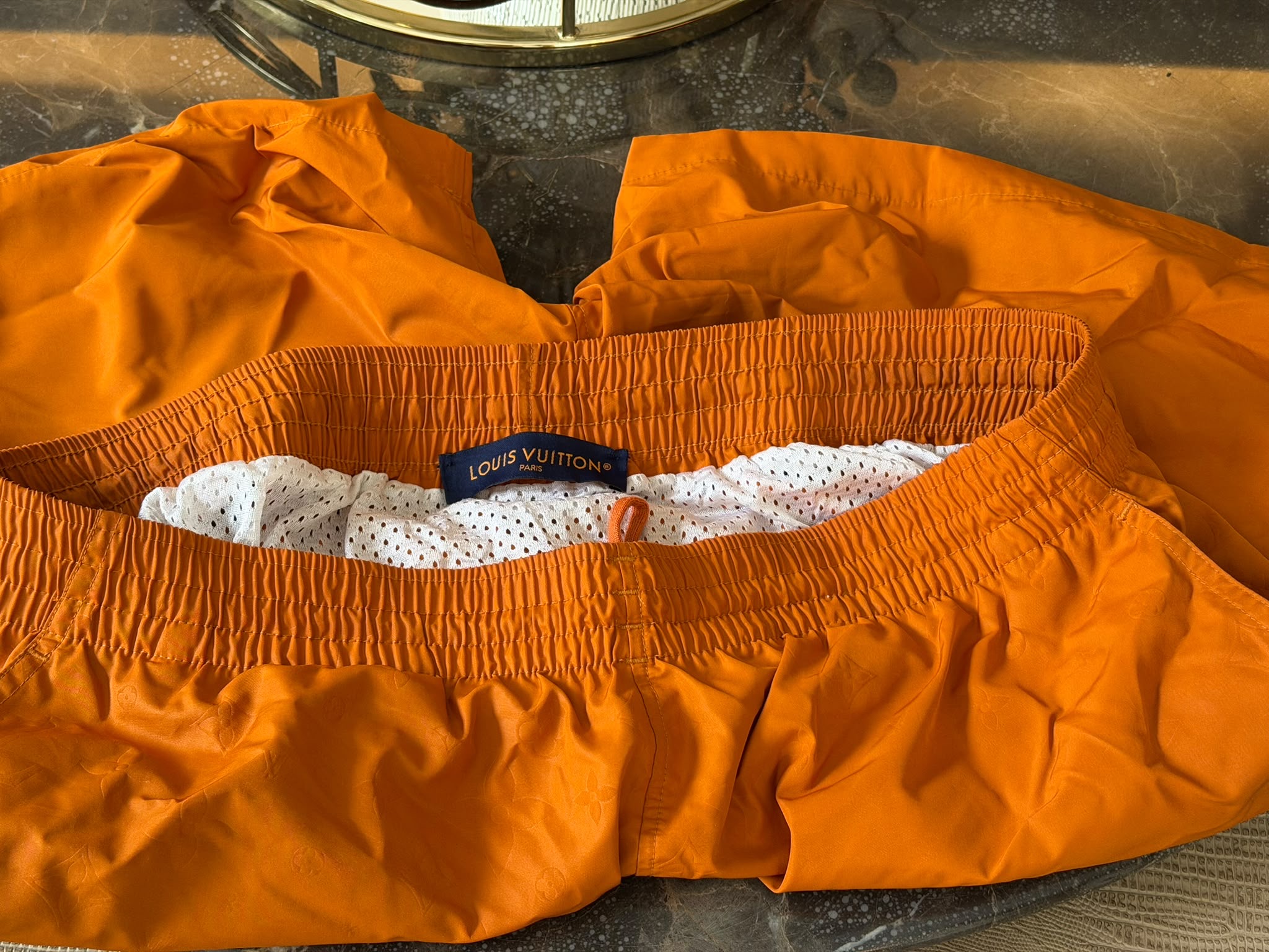 Louis Vuitton Paris waistband label on orange swim shorts