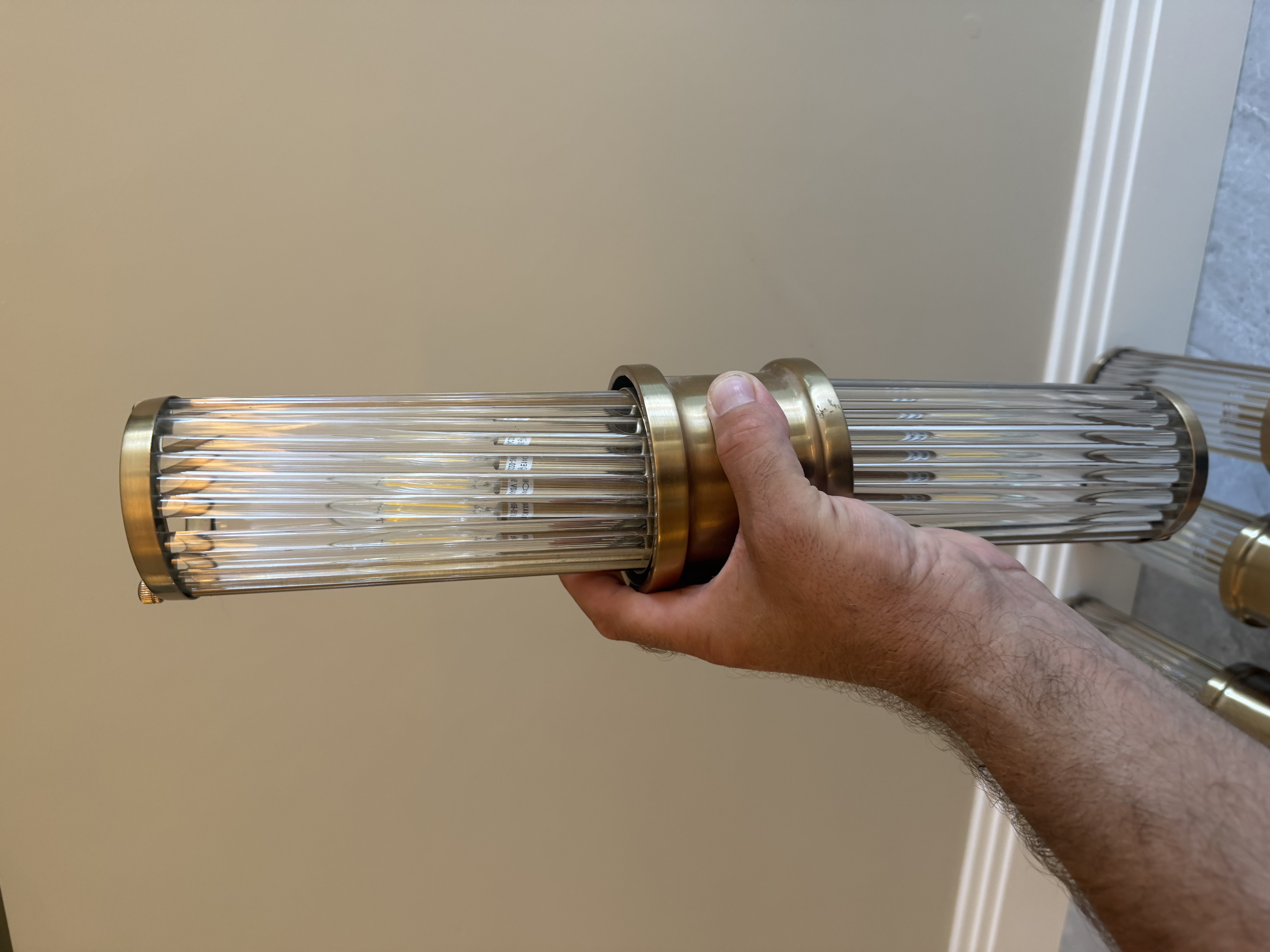 Close-up of Eichholtz matte brass and clear glass wall light